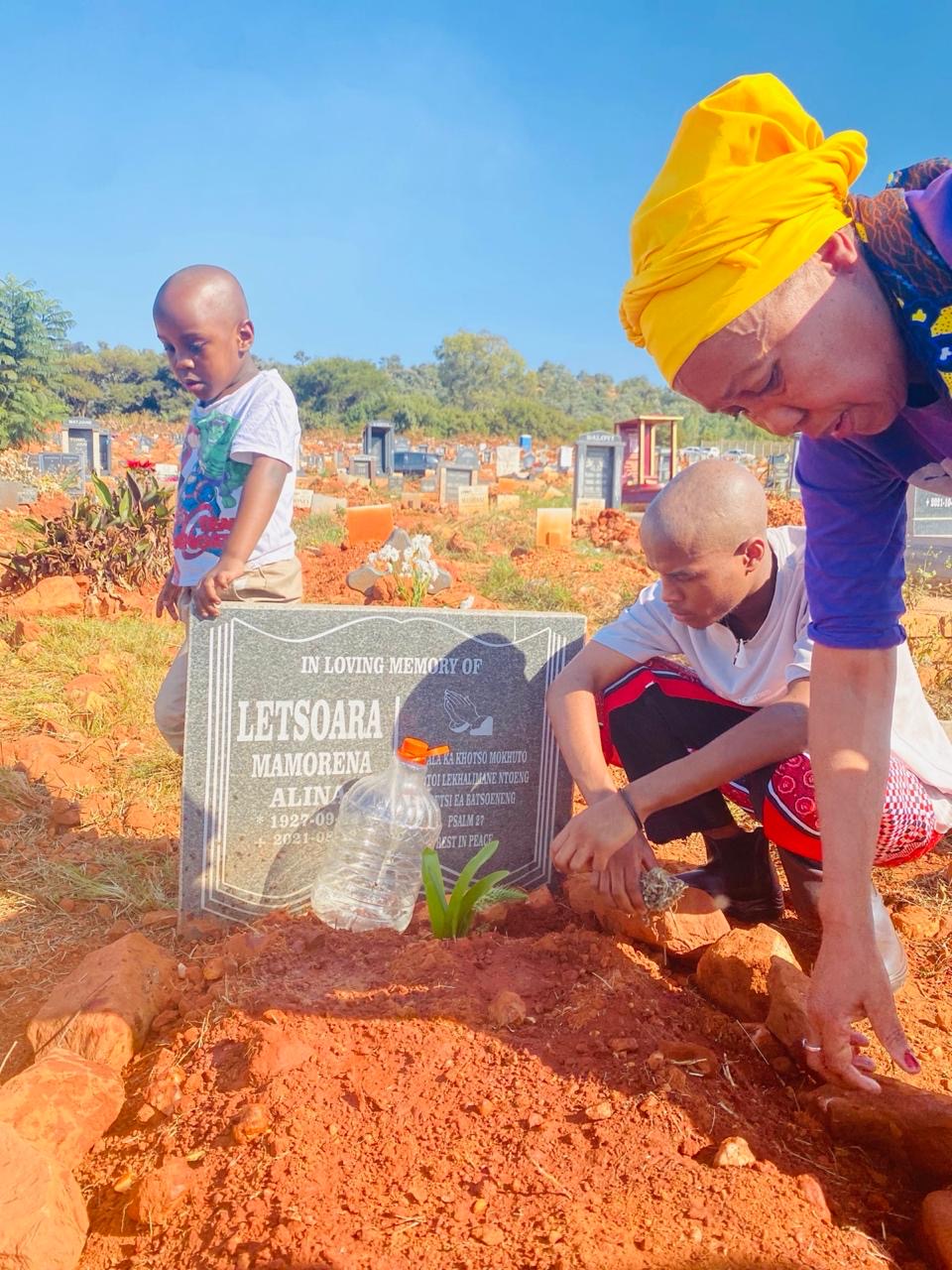 Jerrita and her two sons tending a family grave together