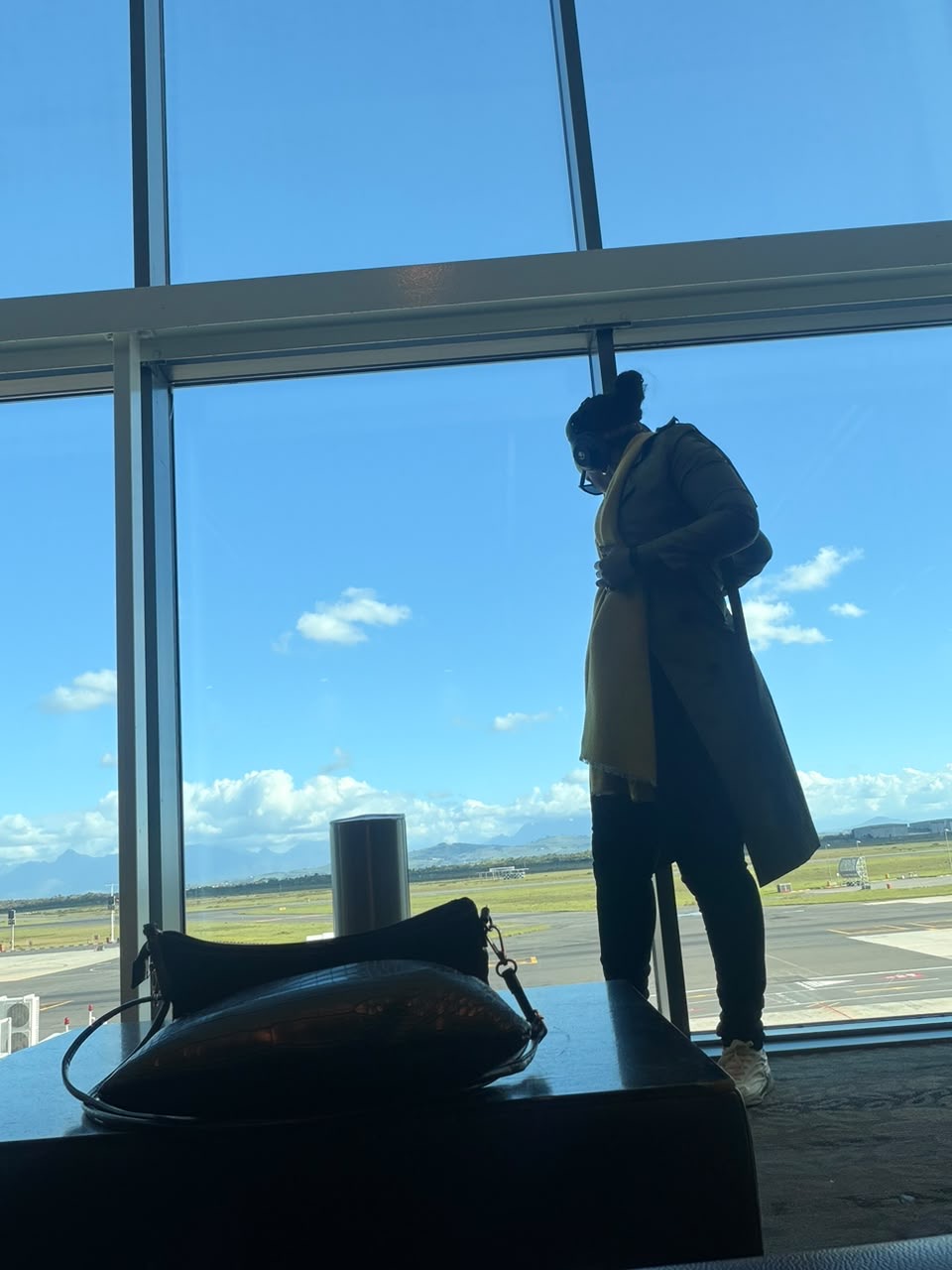 Jerrita at an airport window overlooking the runway and mountains